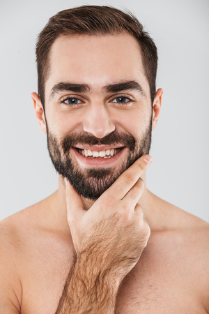 Close up of a young handsome bearded shirtless man standing isolated over white background, posingの写真素材