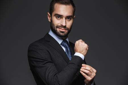 Portrait of a confident handsome businessman wearing suit isolated over black backgroundの写真素材