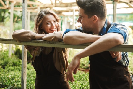 Image of two happy gardeners posing in the nature greenhouse garden talking with each other.の写真素材