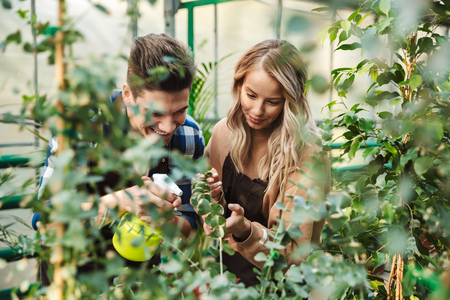 Image of two amazing gardeners posing in the nature greenhouse garden work with flowers plants.の写真素材