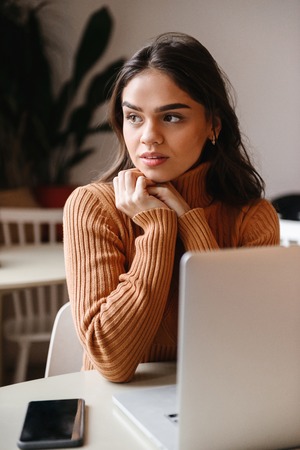 Picture of a young pretty beautiful woman sitting in cafe indoors using laptop computer.の写真素材