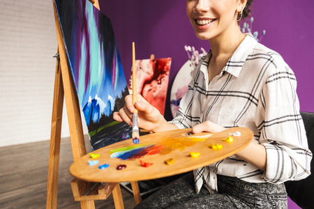 Creative artistic beautiful woman painting at home, holding paletteの写真素材