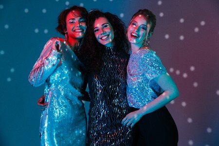 Image of a beautiful young happy women posing isolated with disco ball lights.