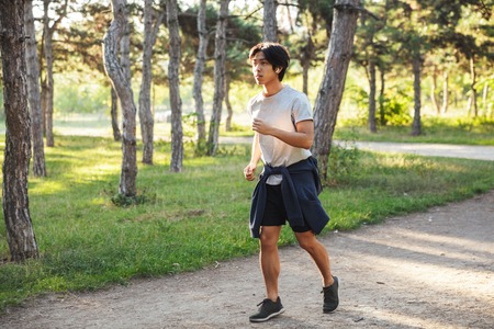 Full length of a confident asian athlete man running at the parkの写真素材
