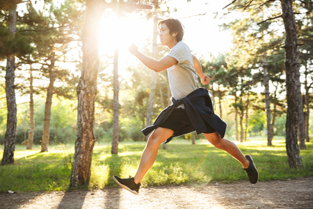 Full length of a confident asian athlete man running at the parkの写真素材