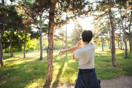 Back view of a young asian athlete man wearing sportswear doing exercises outdoors at the park, stretchingの写真素材
