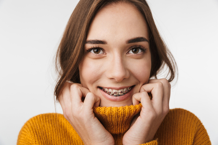 Attractive young woman standing isolated over white background, wearing sweater, posingの写真素材