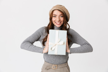 Photo of happy woman 30s wearing hat holding present box isolated over white background