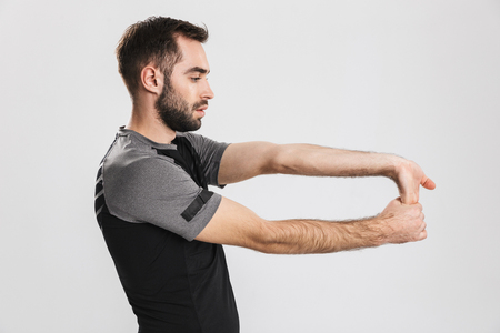 Image of a handsome young sports fitness man posing isolate over white wall background make stretching exercises.の写真素材