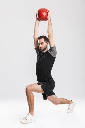 Image of a handsome young sports fitness man posing isolate over white wall background make exercises with ball.の写真素材