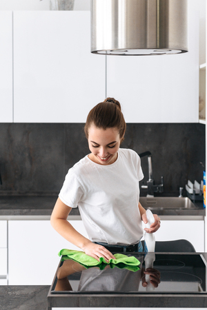 Attractive young woman cleaning kitchen with detergentの写真素材