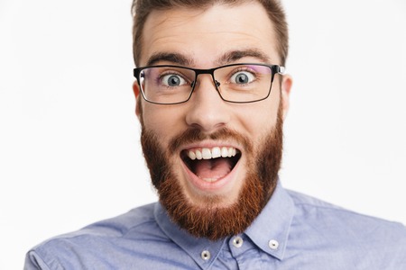 Close up image of Surprised happy bearded elegant man in eyeglasses rejoices and looking at the camera over grey backgroundの写真素材