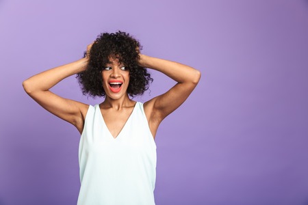 Portrait of a cheerful african woman wearing dress standing isolated over violet background, posingの写真素材