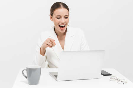 Image of a beautiful happy woman posing isolated over white wall background using laptop computer pointing.の写真素材