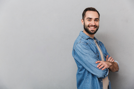 Excited cheerful man wearing shirt isolated over gray background, arms foldedの写真素材