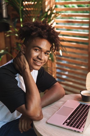Young african teenager student sitting at the cafe indoors