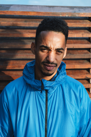 Close up of a young african man wearing hooded jacket standing outdoors
