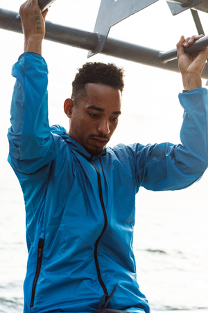 Photo of a strong handsome young african sports man outdoors at the beach sea walking make...