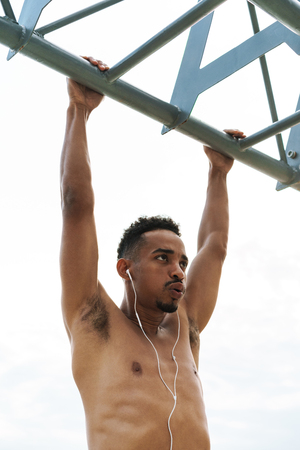 Photo of a strong handsome young african sports man outdoors at the beach sea walking make exercises listening music with earphones.の写真素材