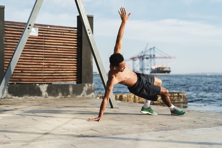 Confident fit african man working out outdoors at the seafrontの写真素材