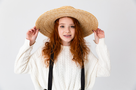 Image of a beautiful young cute girl redhead posing isolated over white wall background wearing hat.の写真素材