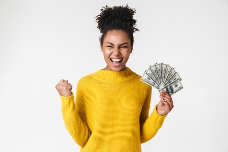 Image of a beautiful young african excited emotional happy woman posing isolated over white wall background holding money.の写真素材