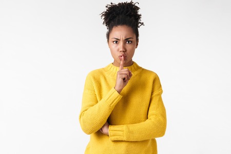 Photo of a beautiful young african woman posing isolated over white wall background showing silence gesture.の写真素材
