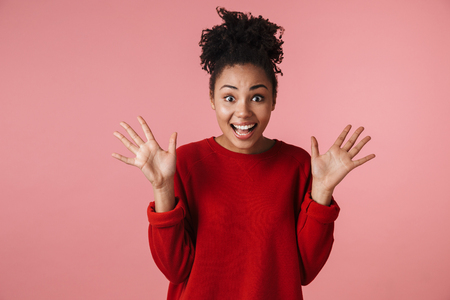 Image of a beautiful amazing young happy excited african woman posing isolated over pink wall background.の写真素材