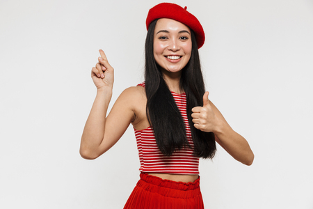 Picture of a beautiful smiling young pretty asian woman posing isolated over white wall background pointing.の写真素材