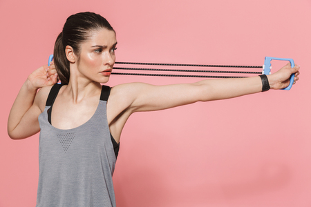 Image of amazing beautiful young pretty fitness woman make sport exercises with equipment isolated over pink wall background.の写真素材