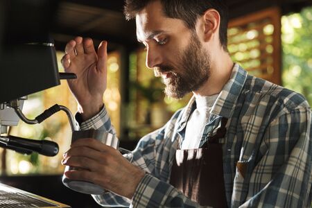 Image of caucasian barista boy wearing apron making coffee while working in cafe or coffeehouse...