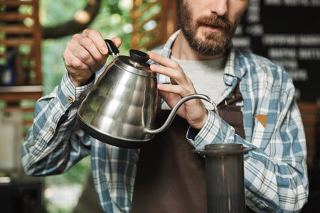Portrait of professional barista man wearing apron making coffee while working in street cafe or coffeehouse outdoorの写真素材