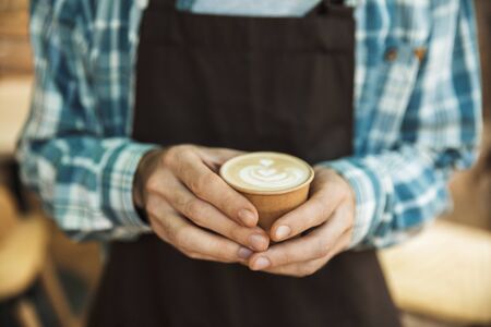 Cropped image of caucasian barista boy wearing apron making coffee while working in cafe or coffeehouse outdoorの写真素材