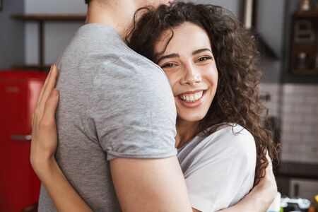 Close up of a happy woman hugging her boyfriend at the living roomの写真素材
