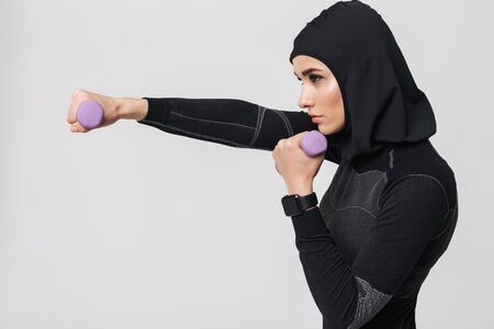 Image of young woman fitness muslim fighter boxer posing isolated over white wall background make exercises with dumbbells.