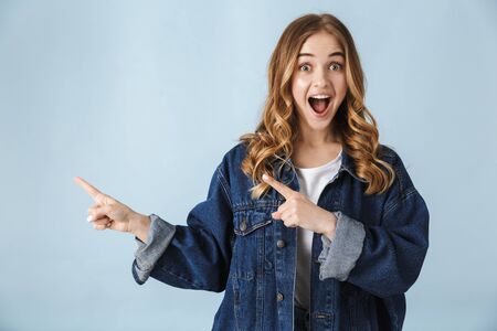 Image of a beautiful young excited pretty woman posing isolated over blue wall background pointing.の写真素材