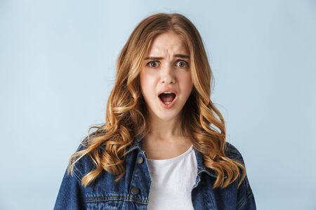 Attractive confused frustrated young girl standing isolated over white background