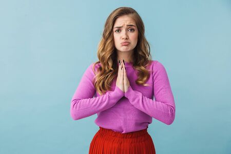 Beautiful young girl wearing casual clothes standing isolated over blue backgound, asking for...