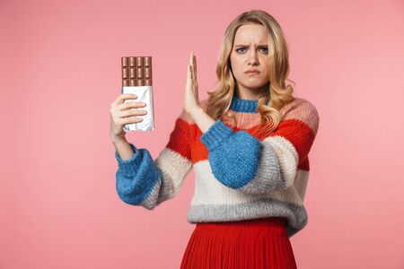 Image of young sad nervous pretty beautiful woman posing isolated over pink wall background holding...