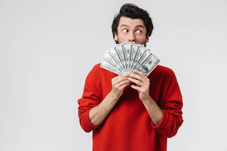 Image of a handsome young excited man posing isolated over white wall background holding money.の写真素材