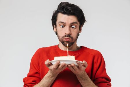 Image of a handsome young excited man posing isolated over white wall background holding birthday cake holidays.の写真素材
