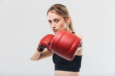 Image of european blond woman 20s dressed in sportswear and boxing gloves working out and during fitness in gym isolated over white wallの写真素材