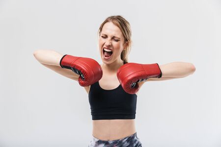Image of delighted blond woman 20s dressed in sportswear and boxing gloves working out and during fitness in gym isolated over white wallの写真素材