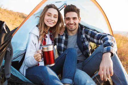 Photo of happy young loving couple outside in free alternative vacation camping drinking hot tea.の写真素材