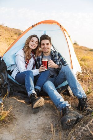 Photo of happy young loving couple outside in free alternative vacation camping drinking hot tea.の写真素材