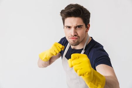 Photo of muscular young man wearing yellow rubber gloves for hands protection clenching fists while cleaning house isolated over white backgroundの写真素材