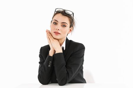 Photo of lovely female worker businesswoman dressed in formal wear looking at camera while working and sitting at desk in officeの写真素材