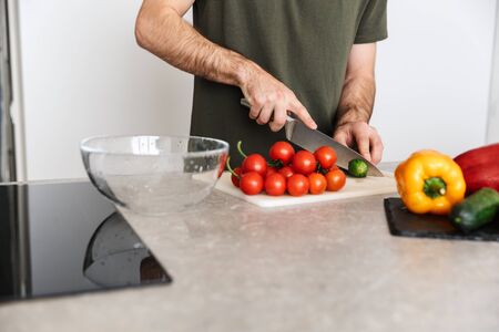 Cropped image of a young handsome man cooking at the kitchen at home have a breakfast.