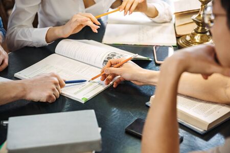 Close up of a teenagers studying at the library together, reading booksの写真素材
