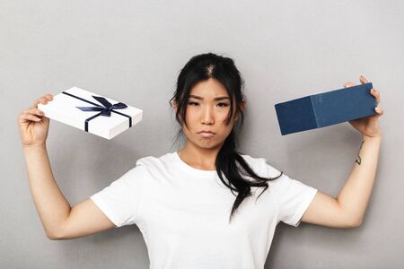 Photo of asian confused sad beautiful young woman posing isolated over grey wall background near...